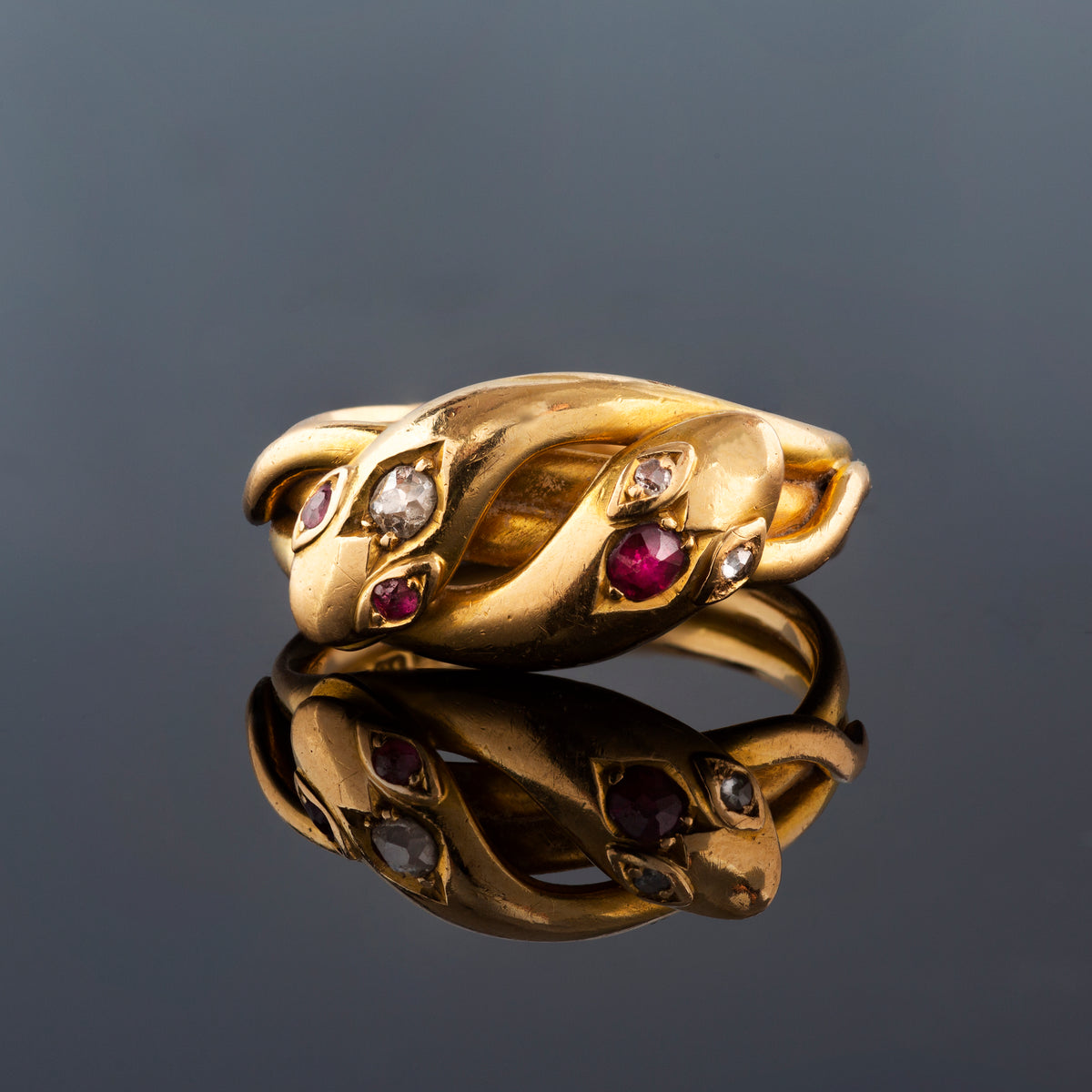 Front view of antique ruby and diamond snake ring on black background, 18ct gold c.1900.