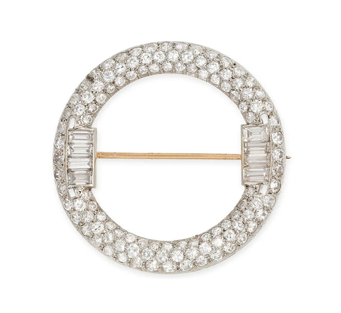Art Deco diamond circle brooch in platinum and 18ct gold, pavé set with old European and baguette cut diamonds, c.1920s on a white background