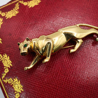 Detailed close up of Cartier Panthère de Cartier brooch with emerald eyes on red Cartier box.
