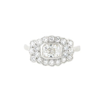 1940s diamond cluster ring in platinum with a cushion shaped old European cut centre diamond surrounded by single cut diamonds in a scalloped border.