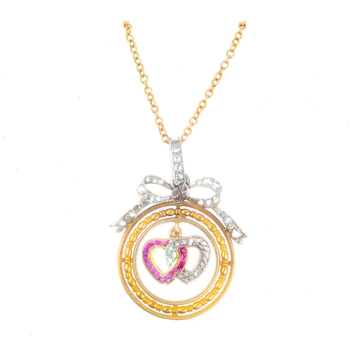 Detail view of Edwardian 18ct gold pendant showing ruby calibre cut heart, diamond pavé heart, and diamond bow above