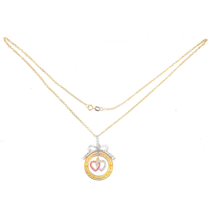 Edwardian c.1910 pendant in 18ct gold with entwined ruby and diamond hearts, framed by engraved gold circle and diamond bow, as worn in the 2020 film Emma