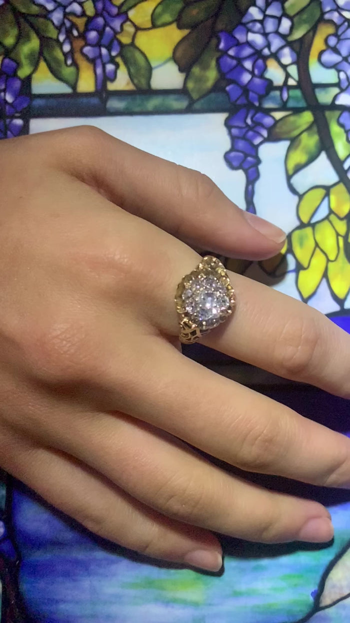 Antique 1880s cushion cut diamond cluster ring in 15ct gold with floral scrollwork, modelled on the hand