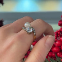 1930s Toi et Moi ring in 18ct gold, shown worn on the hand with a 1.10ct old European cut diamond, natural pearl and diamond set shoulders.