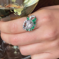 Mid century Colombian emerald and diamond cocktail ring c.1950s, platinum setting with baguette emerald surround and pavé diamond leaf, shown on hand.