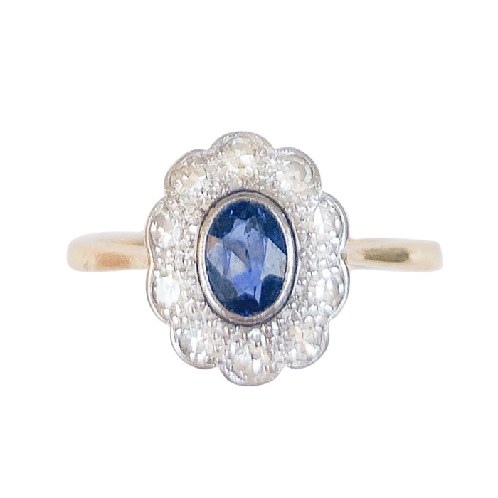 Front view of a Belle Époque sapphire and old European cut diamond cluster ring, featuring a cushion shaped Sri Lankan sapphire in millegrain platinum with a diamond halo, c.1910s.