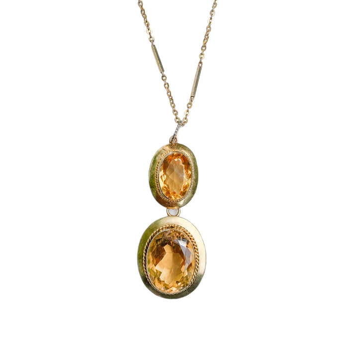 Close up view of an antique Victorian citrine pendant, showing two oval cut citrines set in 15ct gold with fine rope detail, c.1880.