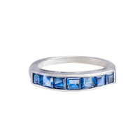 1970s half hoop sapphire ring in 18ct white gold with square-cut channel-set sapphires, shown on white background and worn on hand.