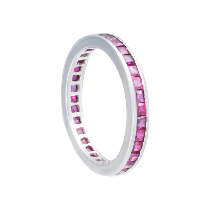 Calibre-cut ruby eternity ring set in 18K white gold, with rubies encircling the full band.