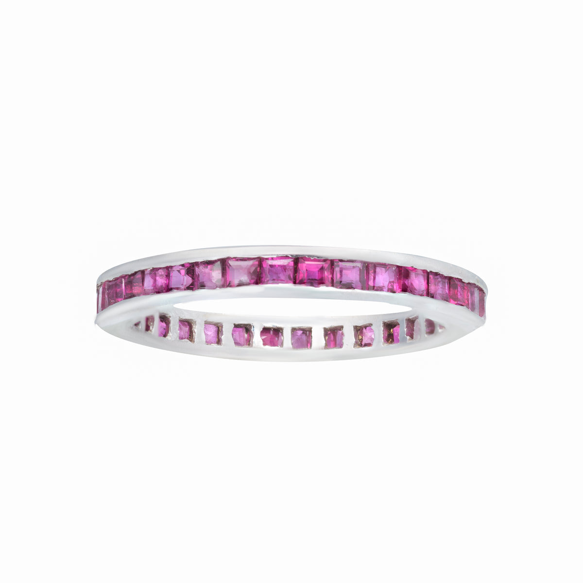 1980s English-made eternity ring featuring calibre-cut rubies in a slim 18K white gold setting.