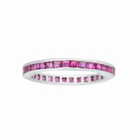 1980s English-made eternity ring featuring calibre-cut rubies in a slim 18K white gold setting.