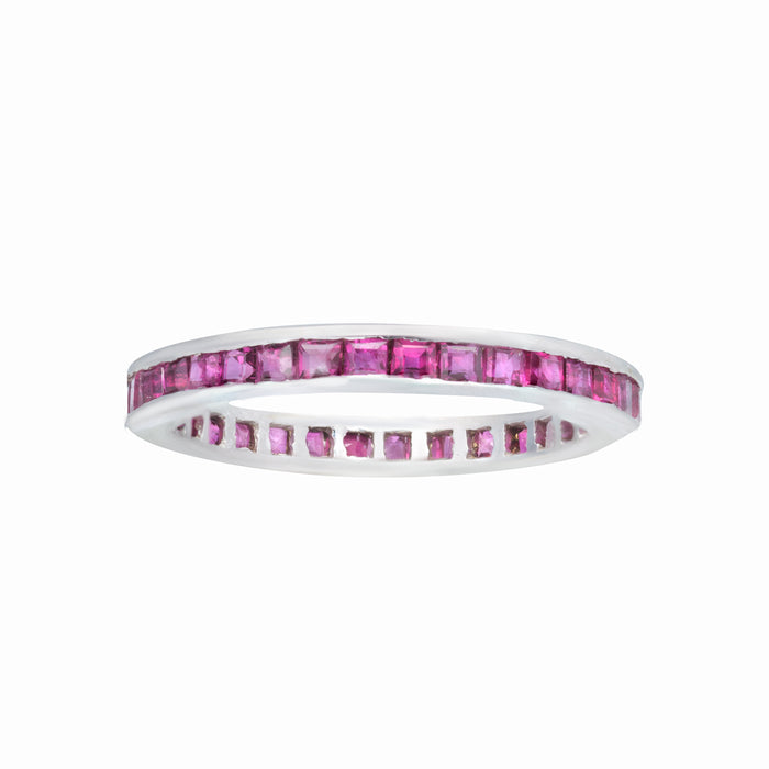 1980s English-made eternity ring featuring calibre-cut rubies in a slim 18K white gold setting.
