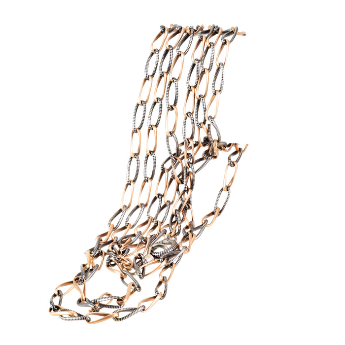 Victorian niello and gilt long chain laid flat, showing alternating silver and gold-toned links.