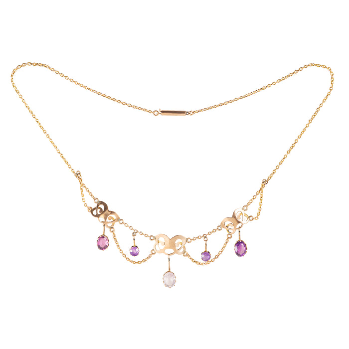 Close-up of antique gold necklace featuring amethysts and rose quartz in pierced gold design