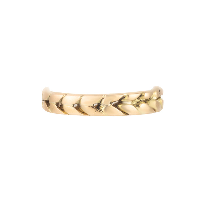 Close-up of textured gold wedding band with chevron detail, photographed flat