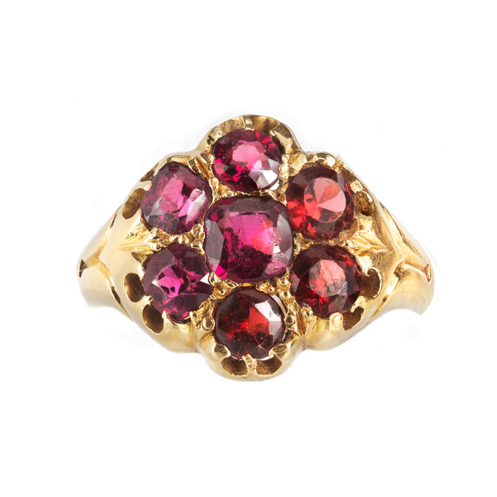 Antique British ring featuring deep red garnets in a floral gold setting