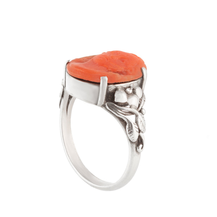 Antique handmade silver ring featuring an orange coral carved face and foliate shoulders, UK size O.