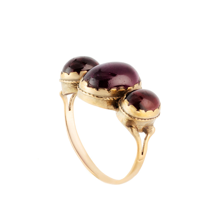 Side view of a 1940s trilogy ring in 9ct gold with domed garnet cabochons and sculpted shoulders.