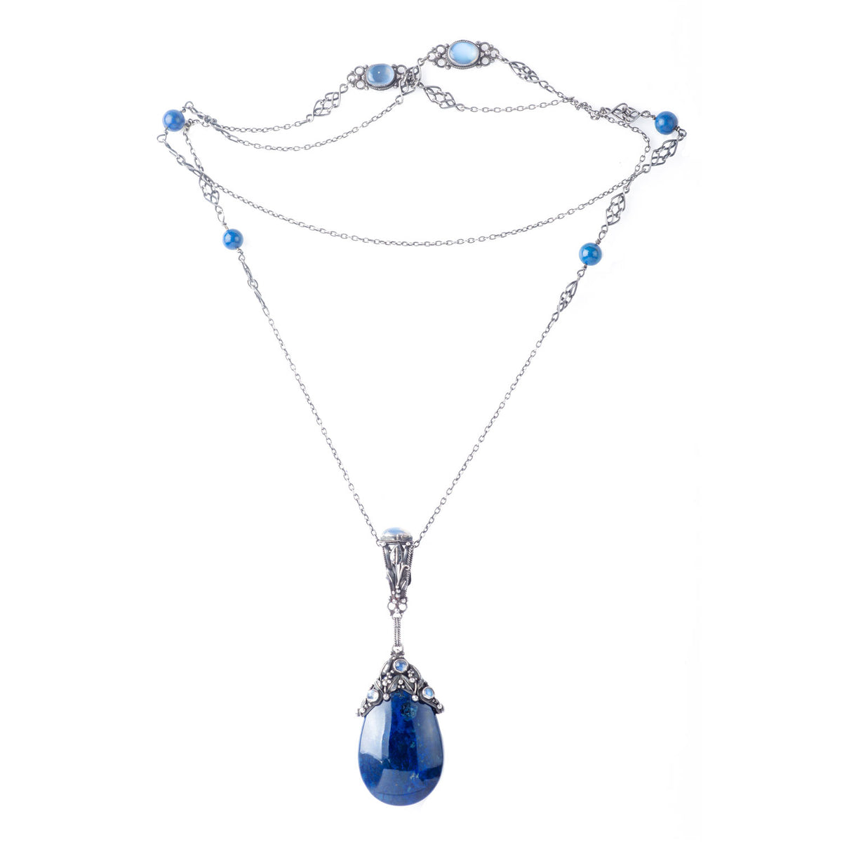 Full view of a long silver necklace by Amy Sandheim, showcasing intricate Arts & Crafts design with moonstone and lapis accents leading to a sculptural lapis pendant.