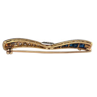 Side profile of Art Deco sapphire and diamond bow brooch showing gold gallery and pin fitting.