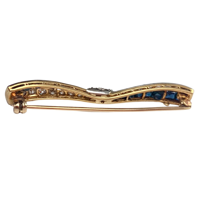 Side profile of Art Deco sapphire and diamond bow brooch showing gold gallery and pin fitting.