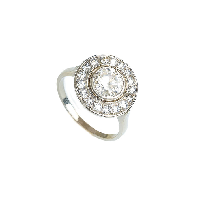 Angled view of French 1920s platinum diamond target ring with central old European cut diamond surrounded by millegrained halo of smaller stones.
