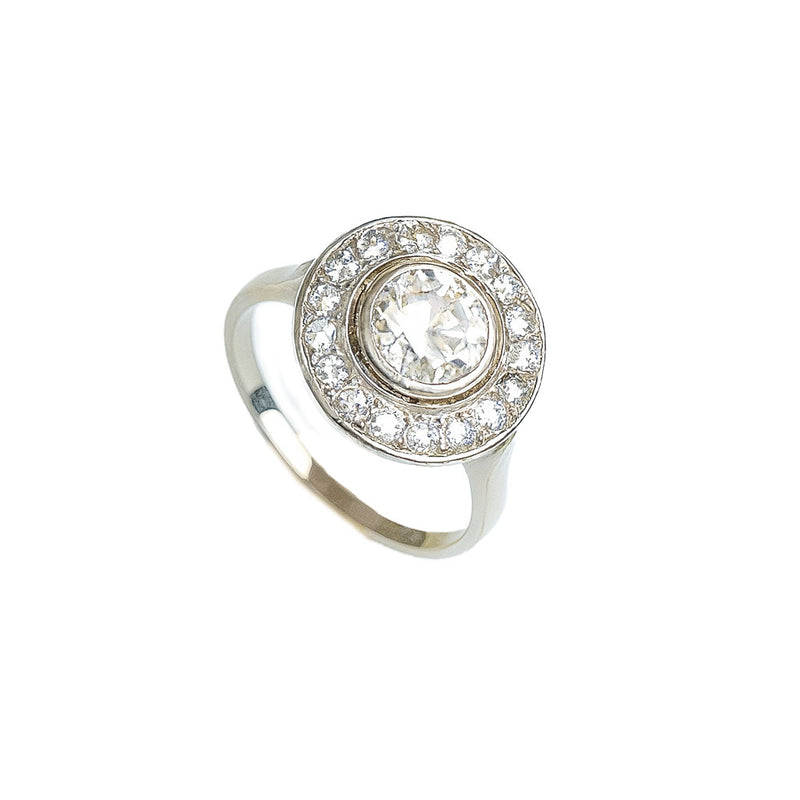 Angled view of French 1920s platinum diamond target ring with central old European cut diamond surrounded by millegrained halo of smaller stones.