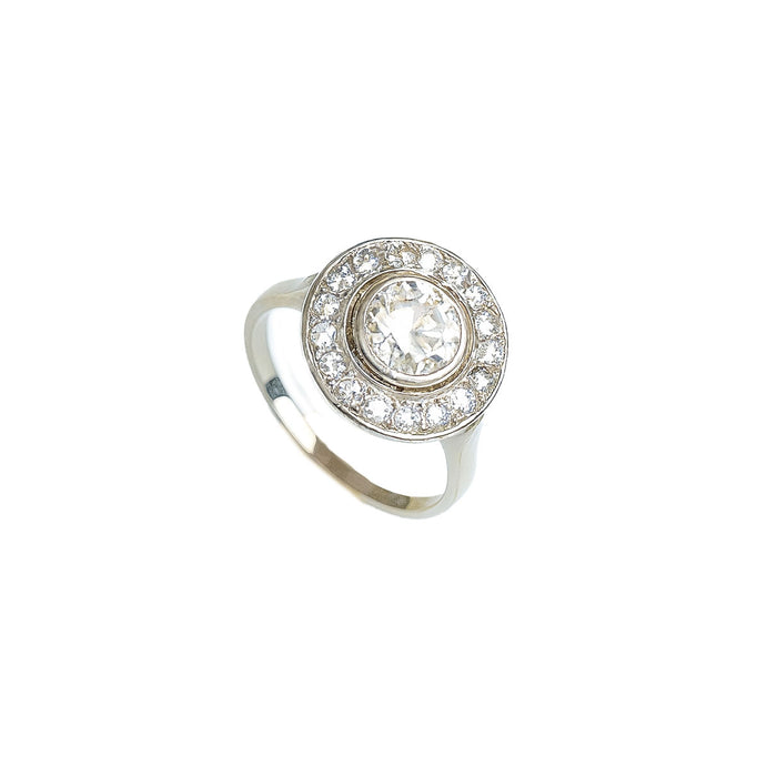 Angled view of French 1920s platinum diamond target ring with central old European cut diamond surrounded by millegrained halo of smaller stones.