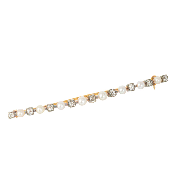 This image features a elegant Pearl & Diamond Bar Brooch. The brooch is crafted in eighteen carat gold and silver, showcasing a series of alternating cushion shaped old mine diamonds and white pearls.