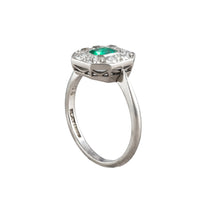 Side view of 1930s Art Deco platinum ring showing open gallery and platinum set old cut diamonds around a bright step cut emerald.