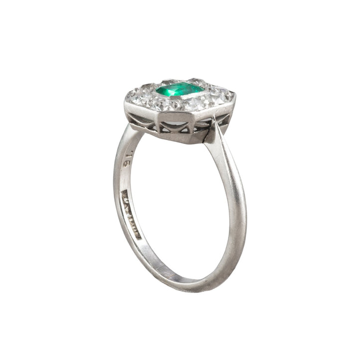 Side view of 1930s Art Deco platinum ring showing open gallery and platinum set old cut diamonds around a bright step cut emerald.
