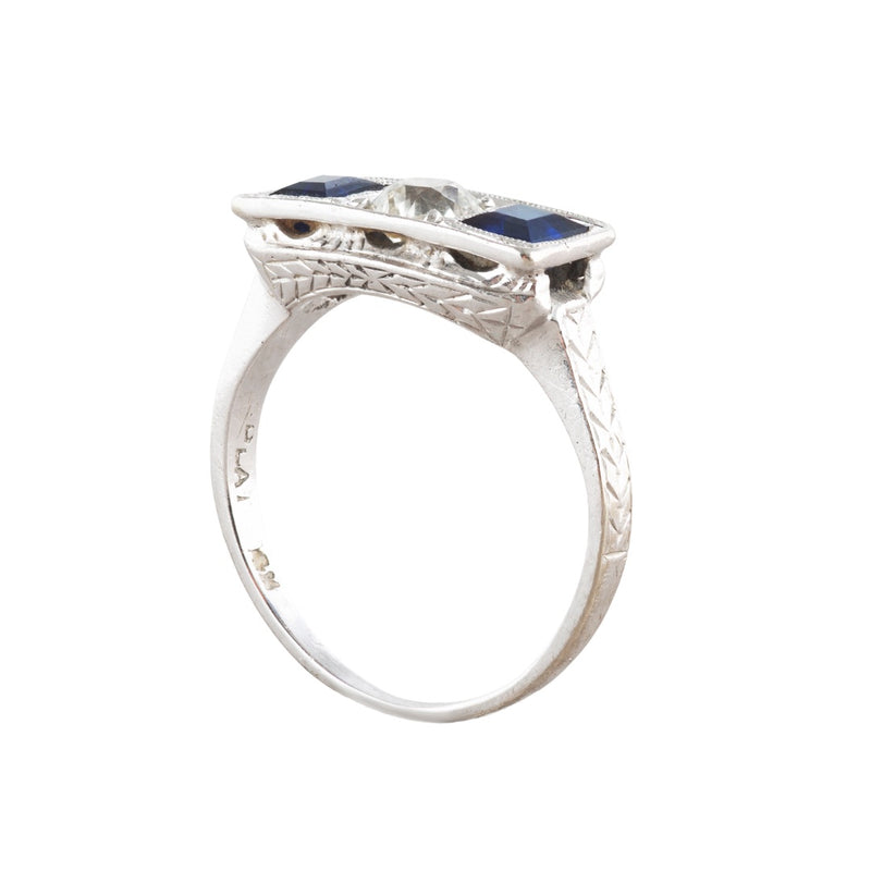 Side profile of 1930s Art Deco sapphire and diamond ring showing engraved shoulders, millegrain setting and pierced gallery detail.