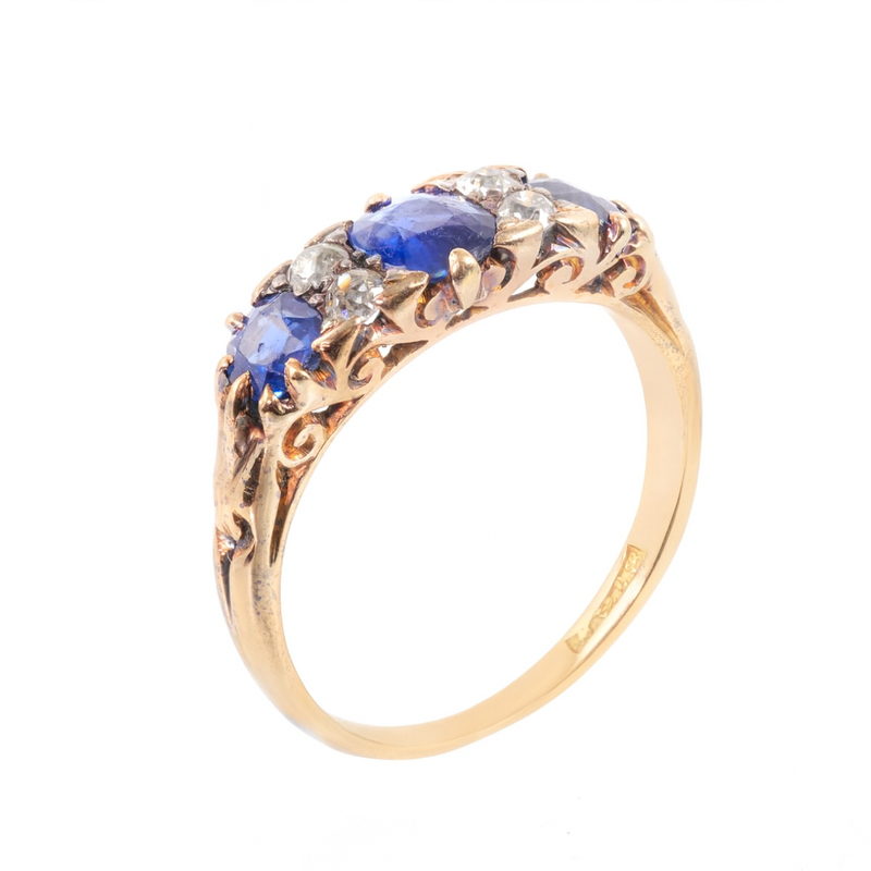 Side view of an Edwardian sapphire and diamond half hoop ring in 18ct gold, showing the ornate carved gallery and deep blue sapphires alternating with old cut diamonds.