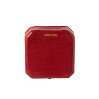 Red 1930s Cartier box with gold logo, octagonal shape.