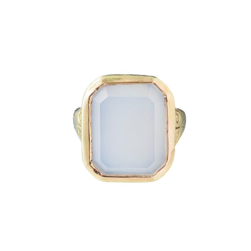 Top view of an octagonal white chalcedony ring set in 14ct gold with engraved shoulders.