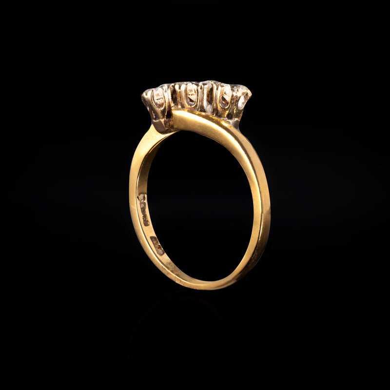 Side view of 18ct gold and platinum three stone diamond twist ring, London 1989, with bright diamonds in platinum claw settings on a tapered gold band.