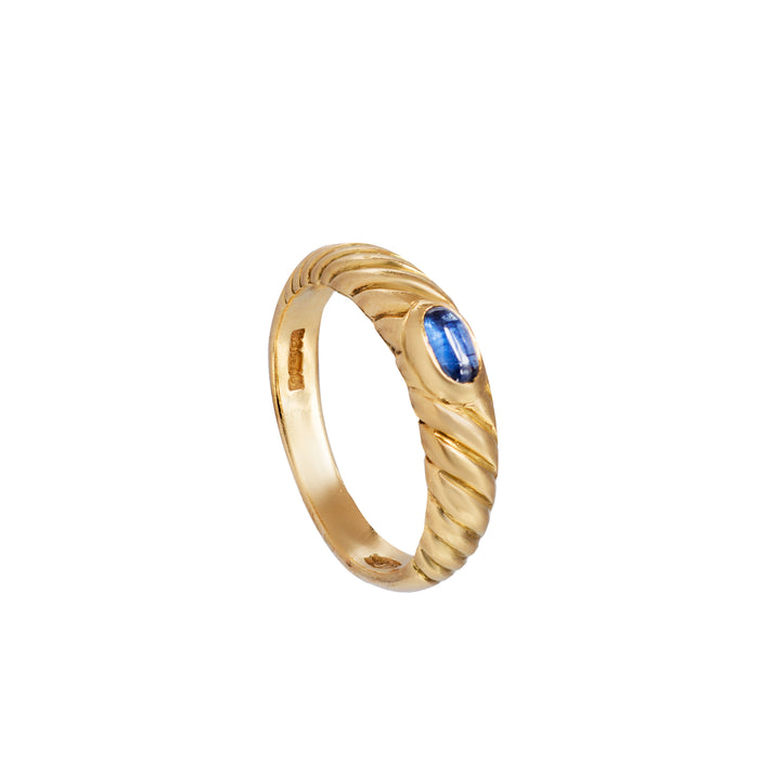 Angled view of 18ct gold ring with deep blue cabochon sapphire and soft sculptural band design
