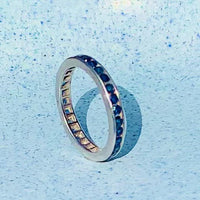 Angled view of 1930s 18ct gold eternity ring featuring a continuous line of blue sapphires.
