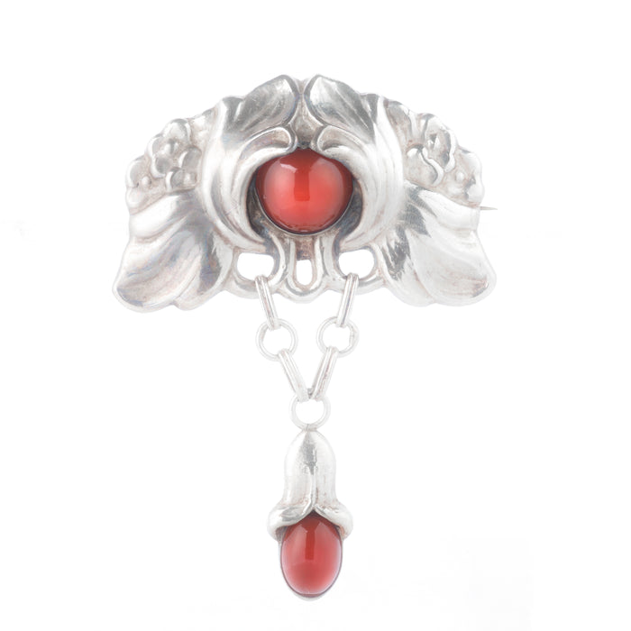 Silver Art Nouveau brooch by Bernhard Hertz set with two carnelian cabochons, photographed on a neutral background.