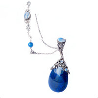 Close-up of a 1930s Amy Sandheim silver pendant necklace featuring a polished lapis lazuli teardrop and moonstone cabochons, suspended from a detailed Arts & Crafts chain.